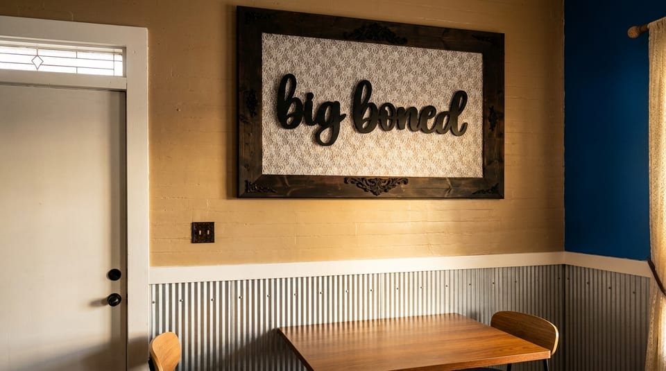 A rustic dining area with a wooden table, chairs, and a "big boned" sign on a textured wall.